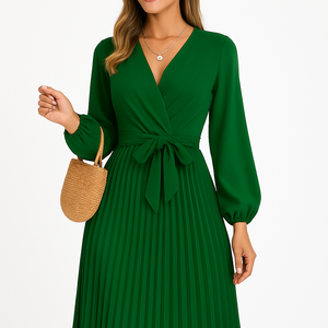Woman wearing elegant green pleated maxi dress with long sleeves and cross-front design holding a straw handbag