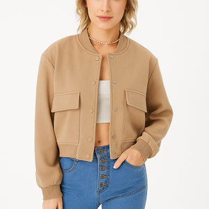 Women’s lightweight cropped bomber jacket in beige with snap buttons and flap pockets, styled with high-waisted jeans and sunglasses.