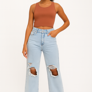 Woman wearing light blue ripped slimming high-waist stretch denim jeans paired with a brown sleeveless crop top and brown heels.