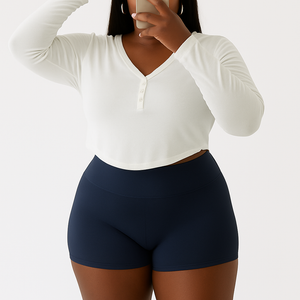 Curvy woman wearing LuxeFlex Seamless Yoga Set high-waisted navy shorts and white long sleeve crop top taking a mirror selfie